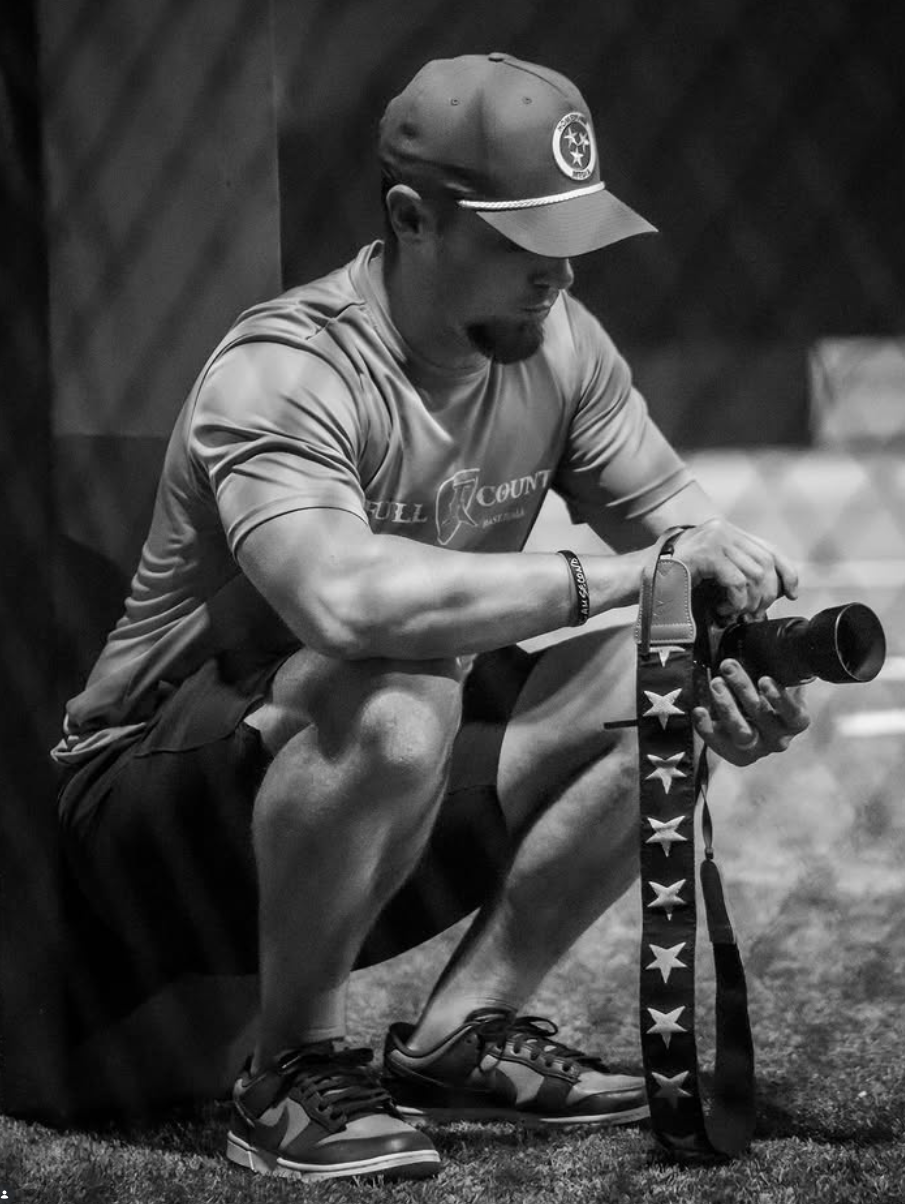 Keith of Hometown Media kneeling with his camera at a baseball facility