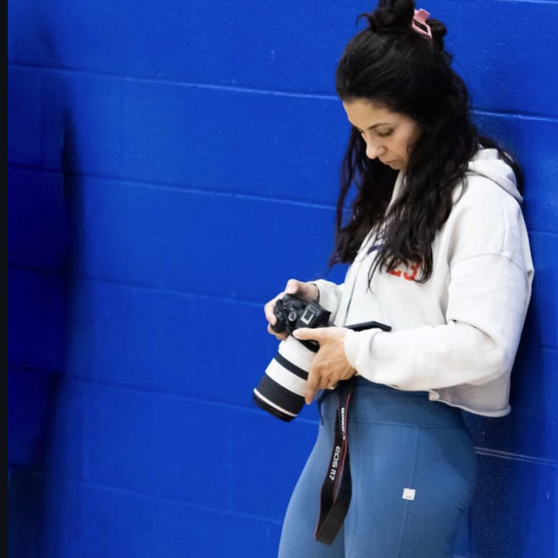 Nicole of Hometown Media reviewing a frame on her camera courtside at a basketball game